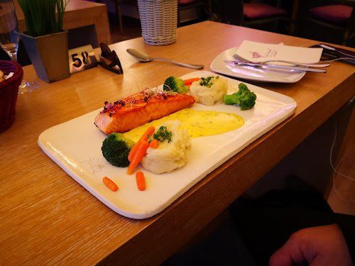 Una persona está sentada en una mesa con un plato de comida encima.