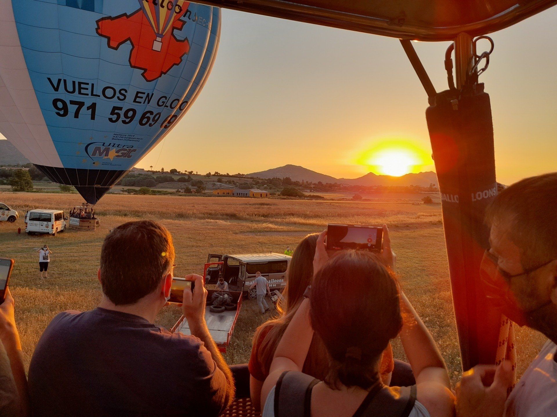 Un grupo de personas está sentada en un globo aerostático mirando la puesta de sol.