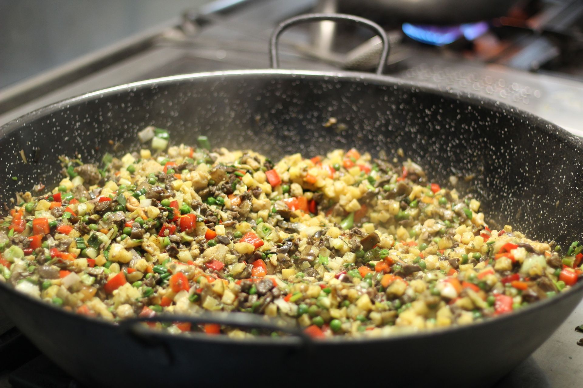 Una sartén llena de verduras se está cocinando en una estufa.