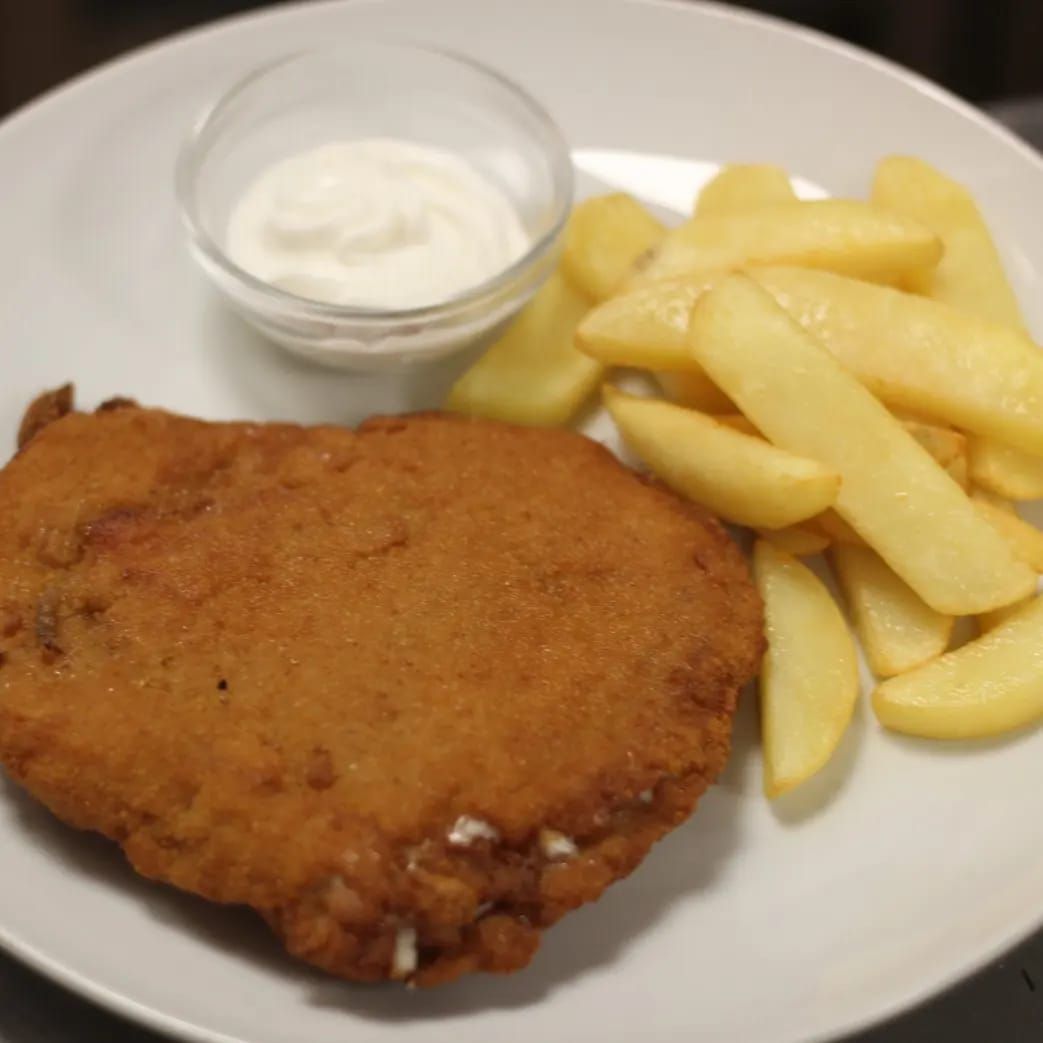 Un plato blanco cubierto con pollo frito y papas fritas.