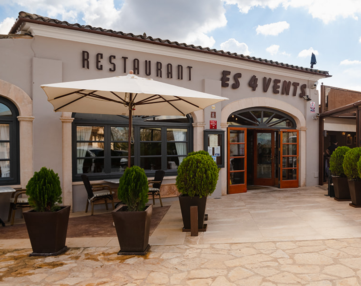 Un restaurante con sombrillas y plantas en macetas delante.