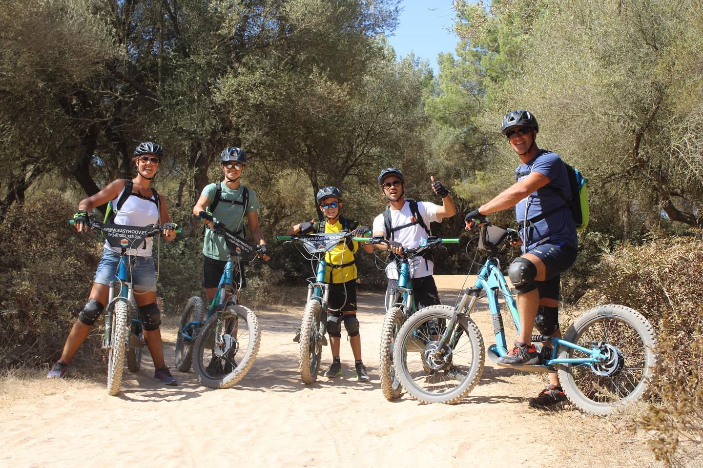 Un grupo de personas de pie junto a bicicletas en un camino de tierra.