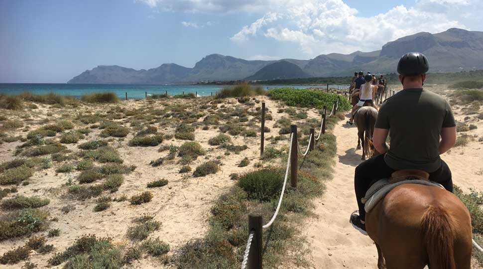 Un grupo de personas monta a caballo por un camino de tierra.