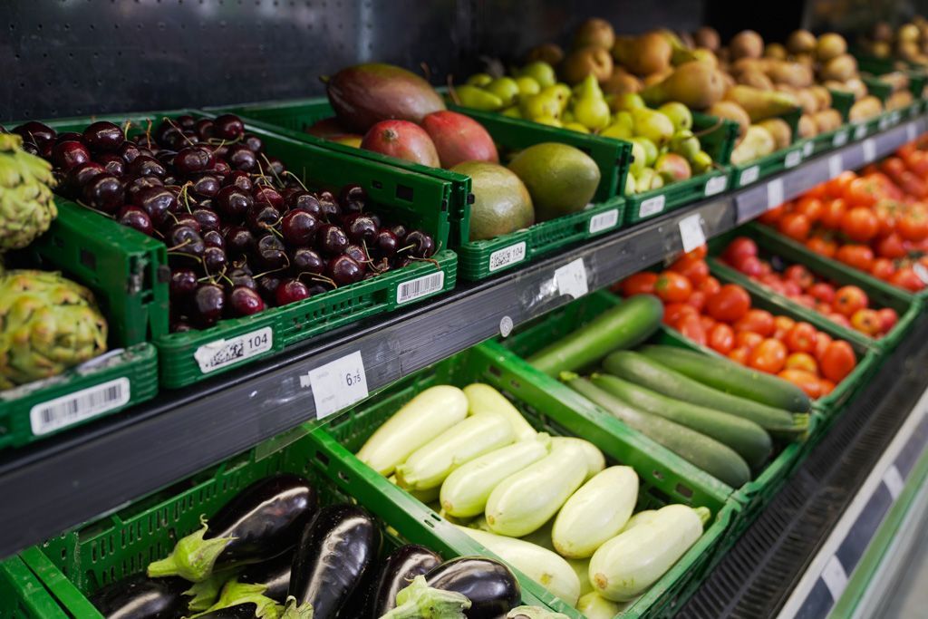 Un estante de un supermercado lleno de frutas y verduras.