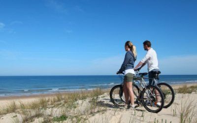 Un hombre y una mujer van en bicicleta por una playa.