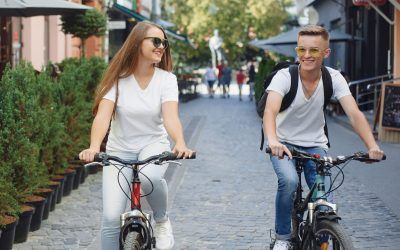Un hombre y una mujer van en bicicleta por una calle adoquinada.