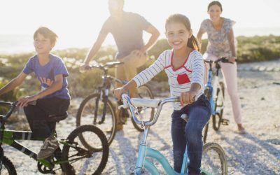 Una familia está montando bicicletas en la playa.
