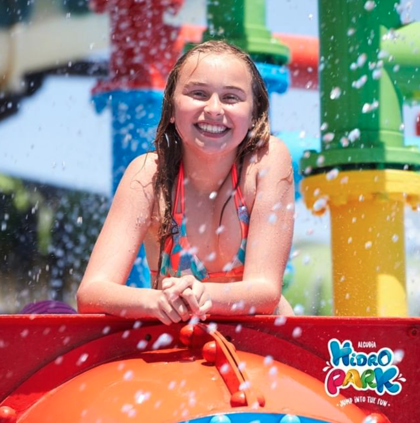 Una chica en bikini está sonriendo en un parque acuático.