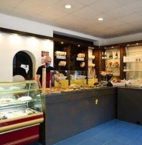 Un hombre está de pie detrás de un mostrador en una panadería.