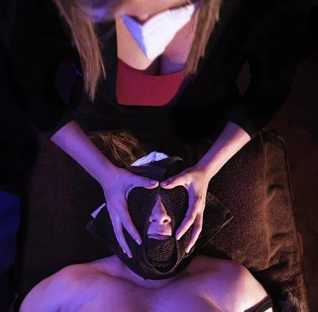 Una mujer está haciendo una forma de corazón con sus manos sobre la cara de un hombre.