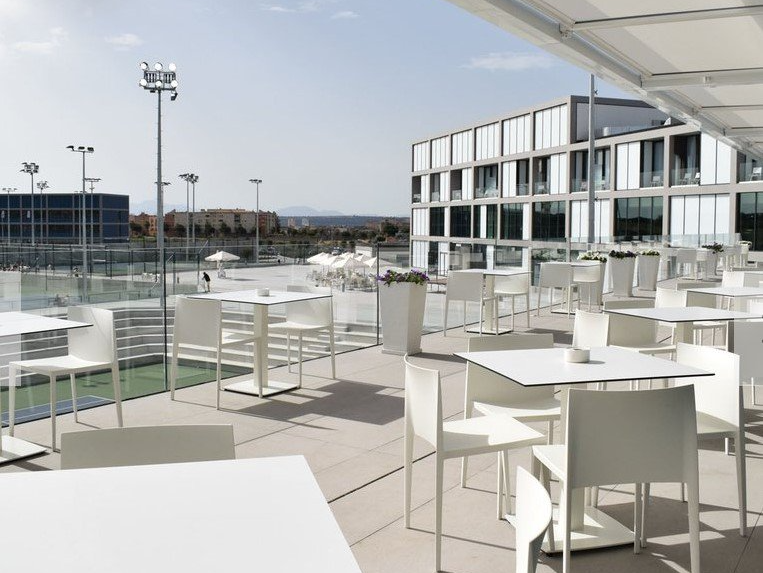 Un restaurante con mesas y sillas blancas frente a un gran edificio.