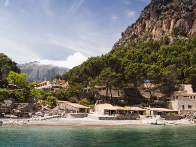 Un pequeño pueblo a la orilla de un lago con montañas al fondo.