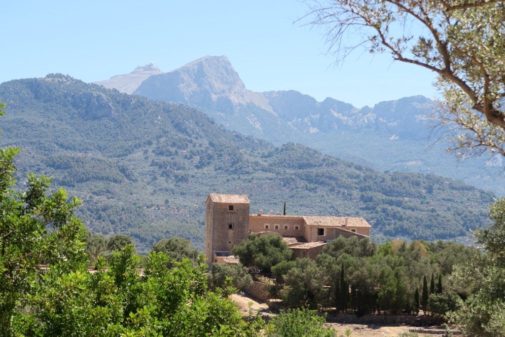 Un castillo en la cima de una colina con montañas al fondo.