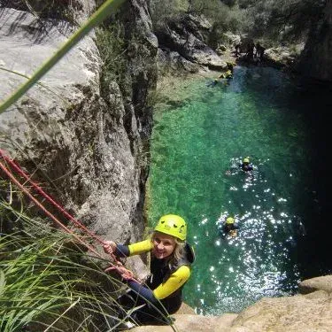 Una niña que lleva un casco amarillo está colgando de una cuerda en el agua.