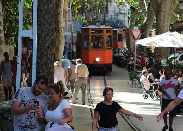 Un grupo de personas camina por una calle frente a un tren.