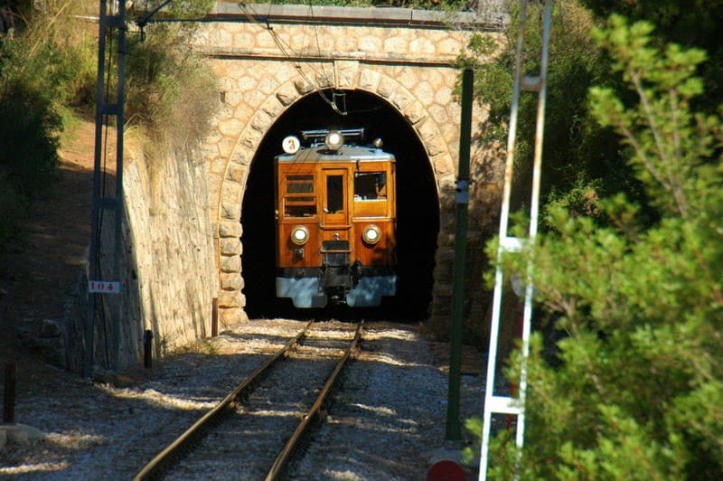 Un tren está saliendo de un túnel sobre las vías.
