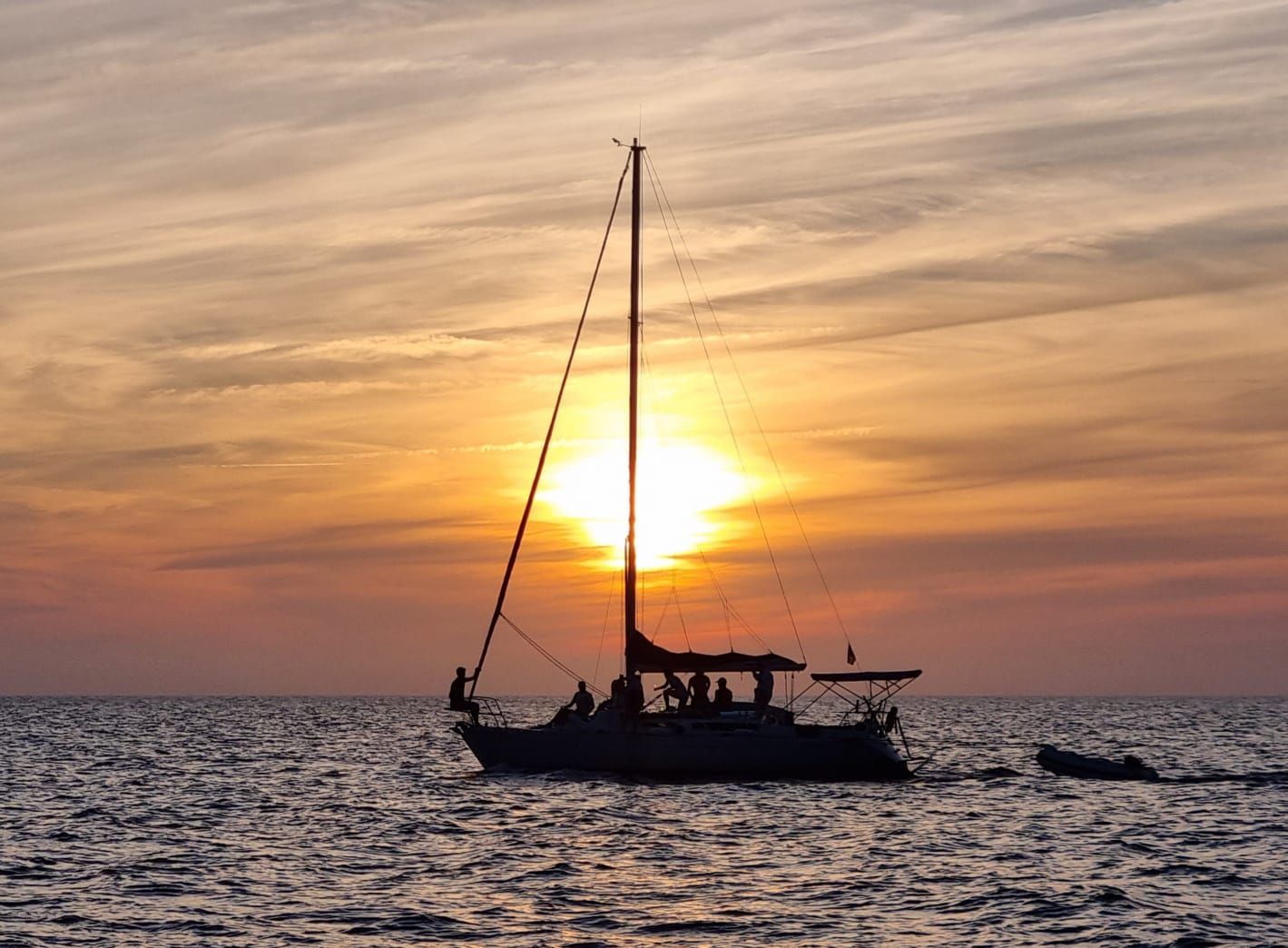 Un velero flota sobre un cuerpo de agua al atardecer.