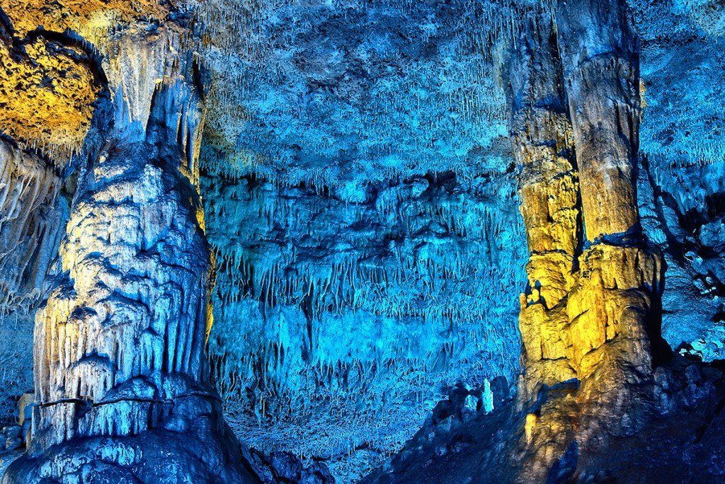 Una cueva azul y amarilla con muchas rocas y árboles.