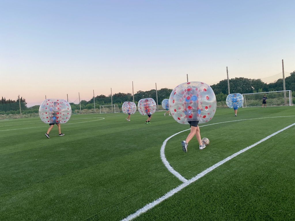 Un grupo de personas está jugando al fútbol burbuja en un campo de fútbol.