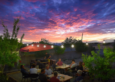 Un grupo de personas están sentadas en mesas frente a una puesta de sol.