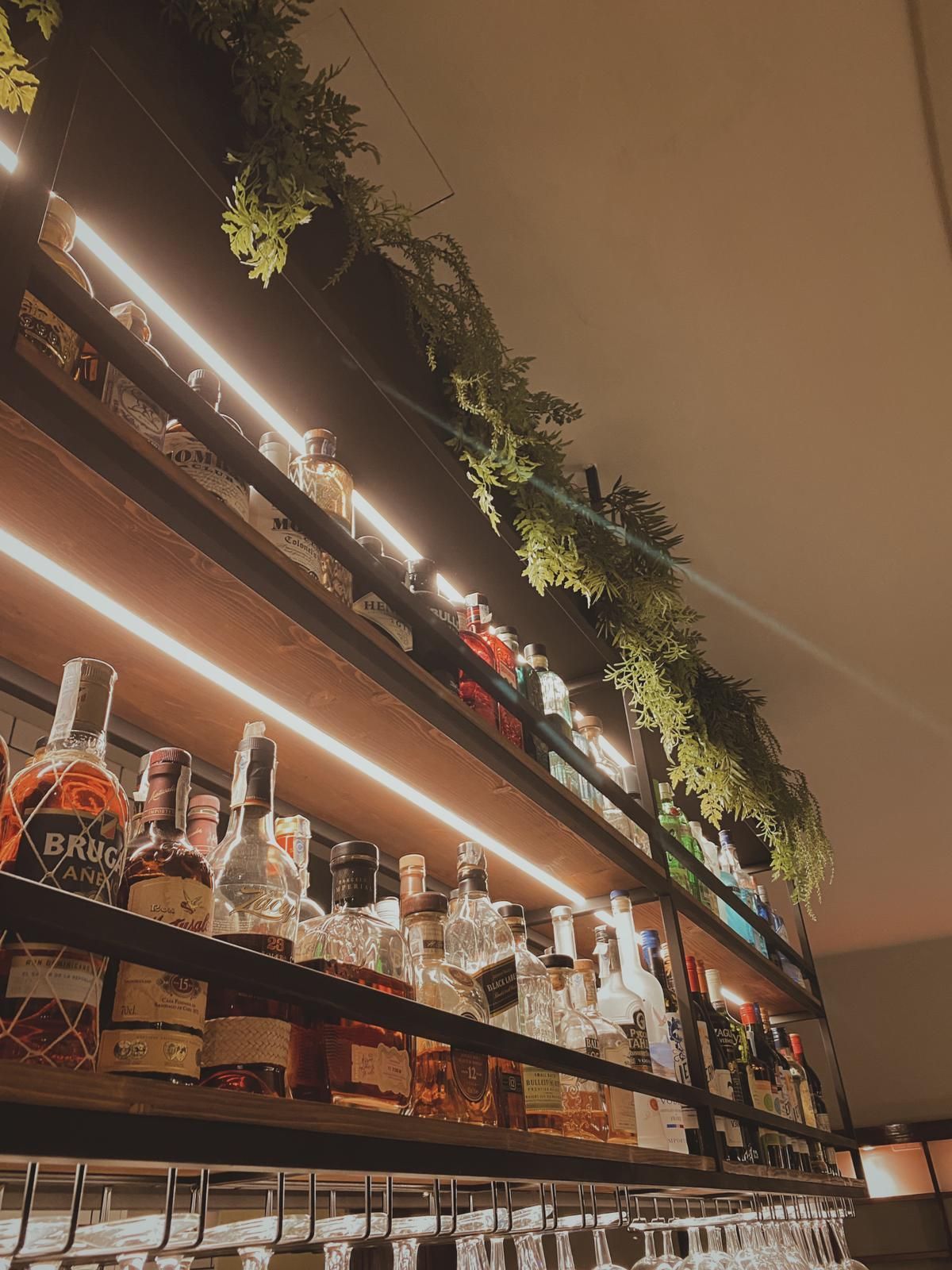Una fila de estantes llenos de botellas de licor y copas de vino.