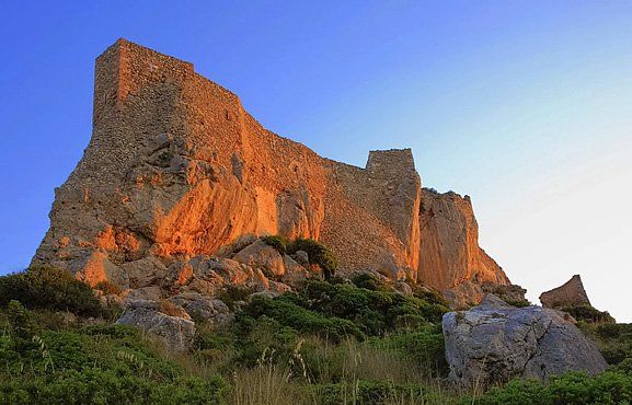 Una gran formación rocosa en la cima de una colina con un cielo azul de fondo.