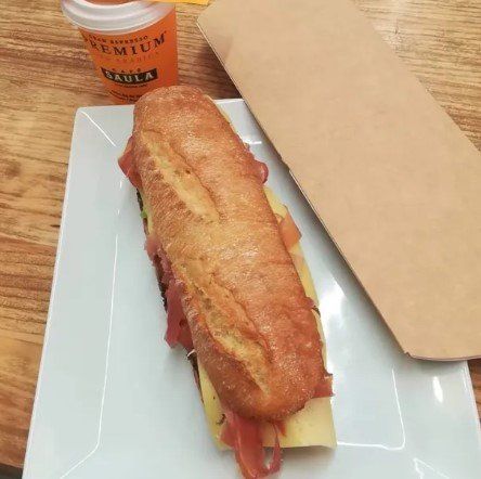 Un sándwich en un plato blanco junto a una taza que dice premium