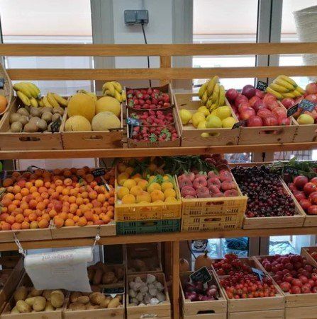 Una variedad de frutas y verduras se exhiben en un estante de madera.