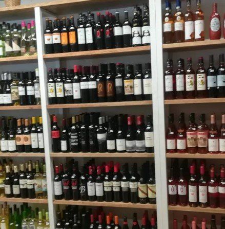 Estantes llenos de botellas de vino, incluida una que dice rr.
