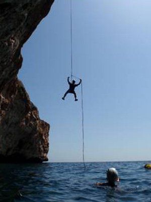 Un hombre está colgando de una cuerda en el océano.