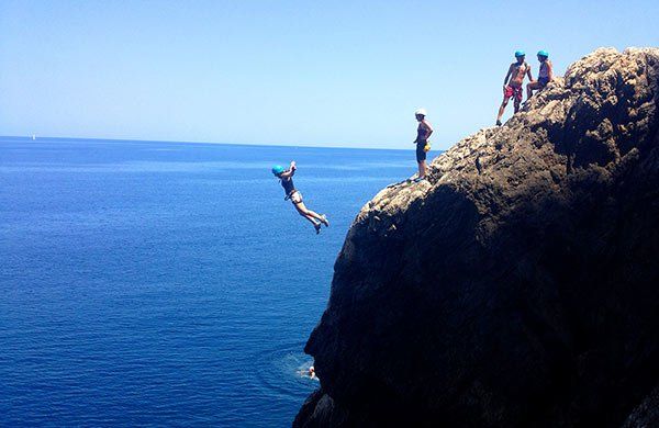 Una persona está saltando desde un acantilado al océano.