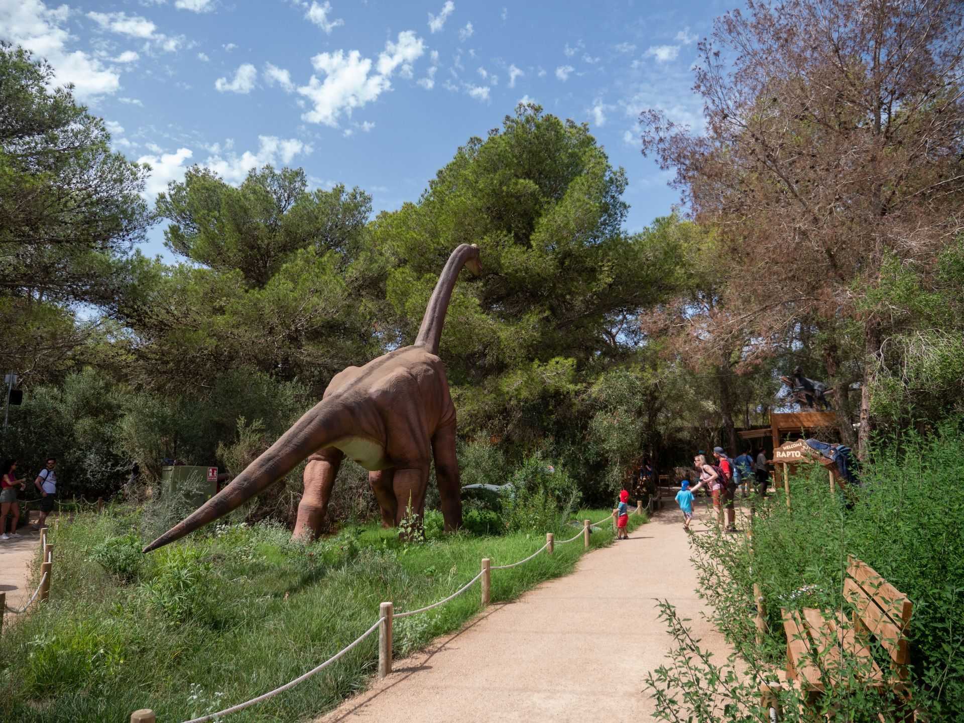 Un gran dinosaurio está parado en el medio de un parque.