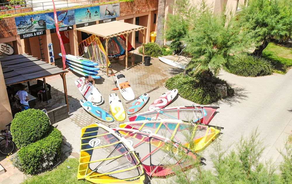 Un montón de tablas de surf están colocadas delante de un edificio.