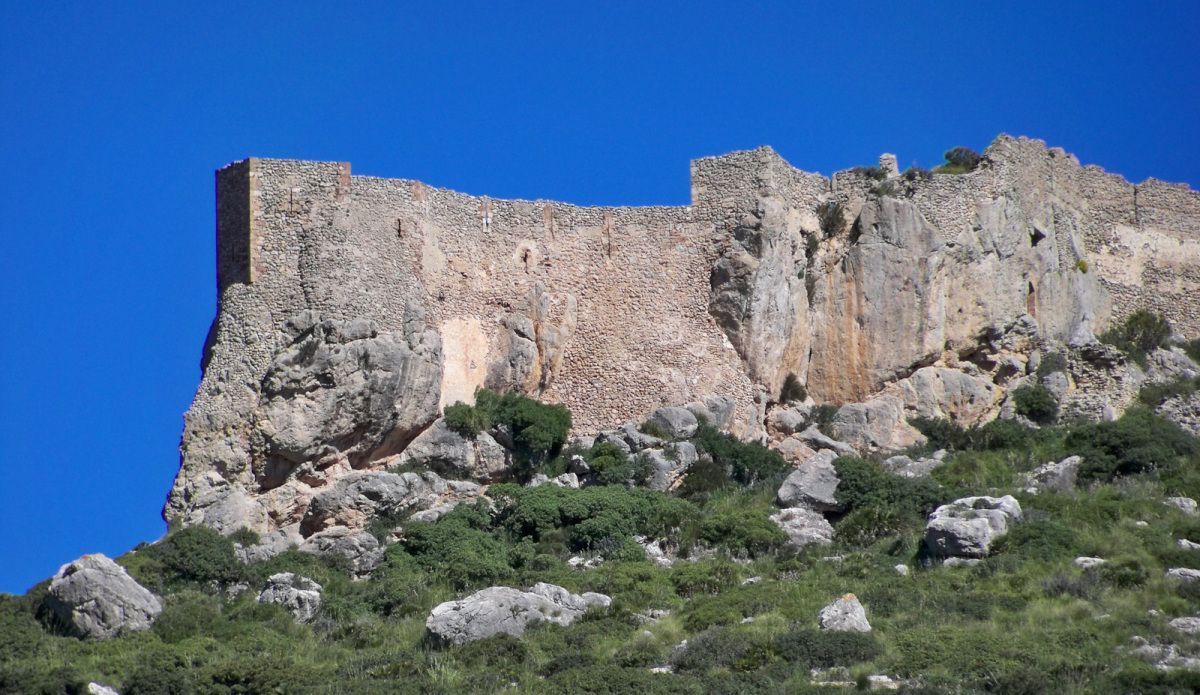 Una gran formación rocosa en la cima de una colina con un cielo azul de fondo.