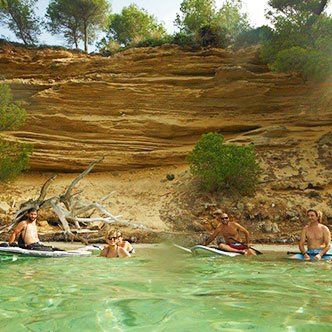 Un grupo de personas están sentadas en tablas de surf en el agua.