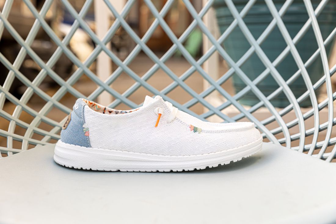 Un par de zapatos blancos encima de una silla azul.