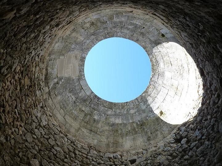 Mirando hacia el cielo a través de un agujero en una pared de piedra.