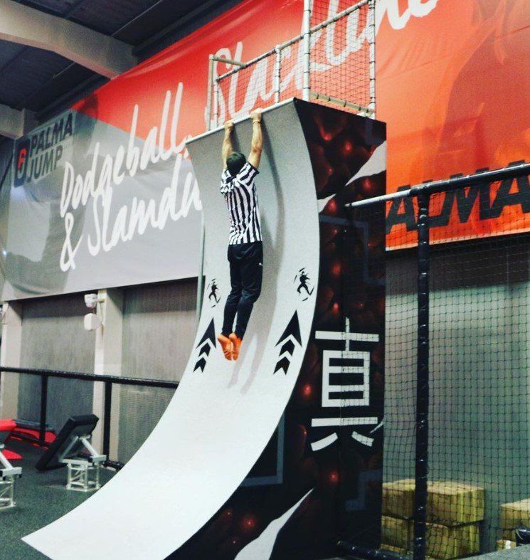 Un hombre colgado de una pared con un cartel que dice baloncesto y se para