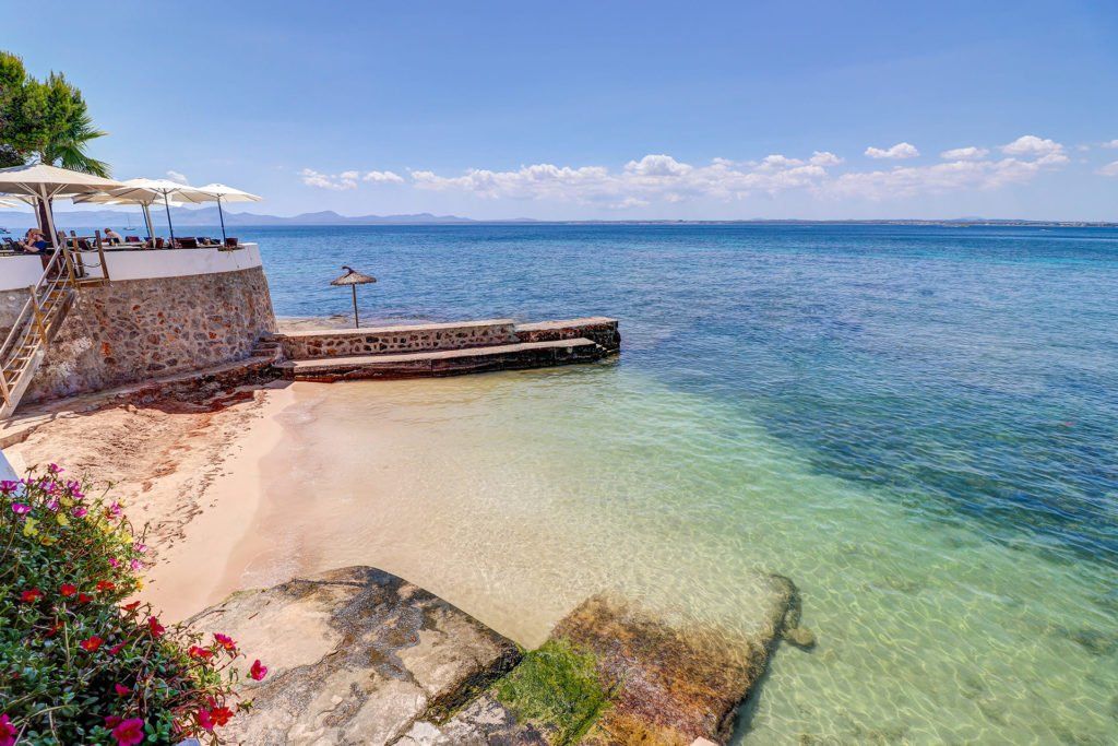 Una playa con muelle y sombrillas al lado del océano.