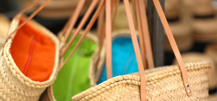 Un grupo de bolsas de mimbre de colores colgando de una percha.