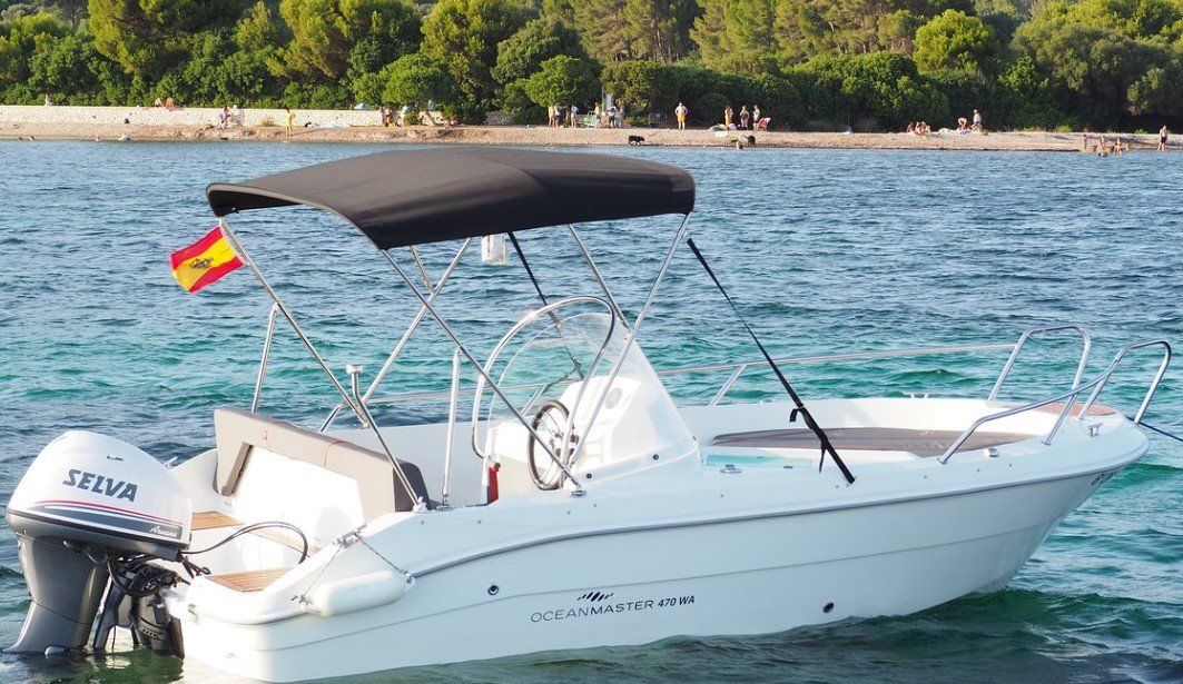 Un barco blanco con un dosel negro flota sobre un cuerpo de agua.