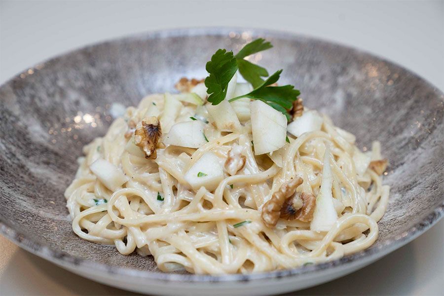 Un primer plano de un plato de pasta con verduras sobre una mesa.