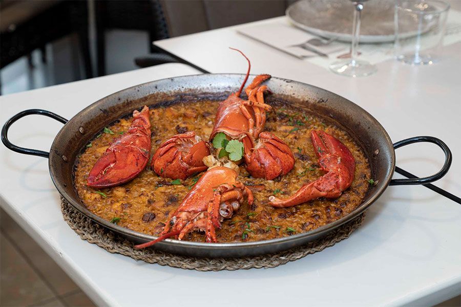 Una sartén llena de langostas y arroz sobre una mesa.