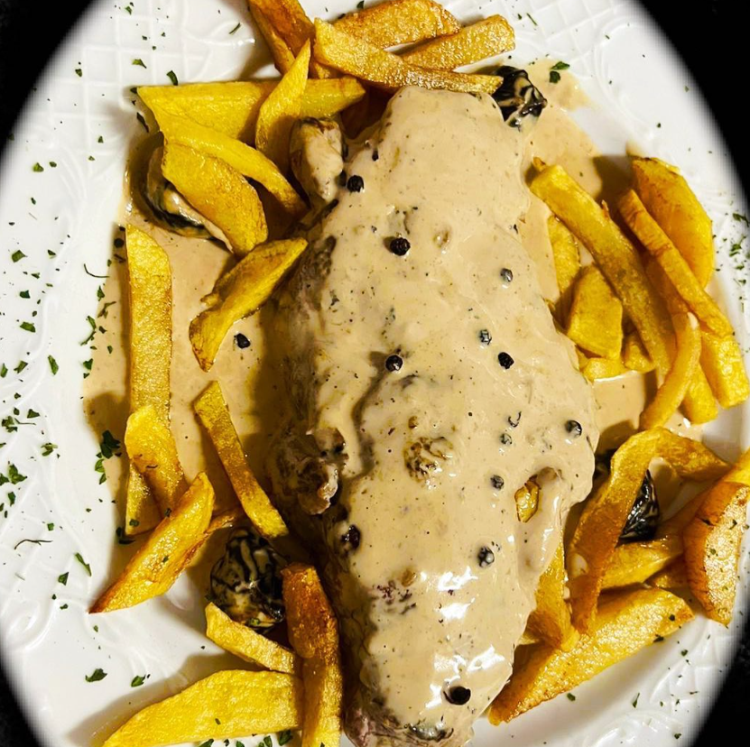 Un plato de comida con papas fritas y salsa encima.