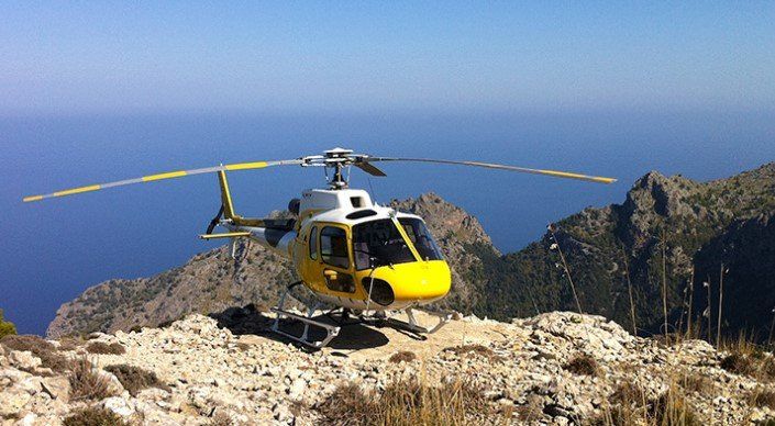 Un helicóptero amarillo y blanco está sentado en la cima de una montaña.