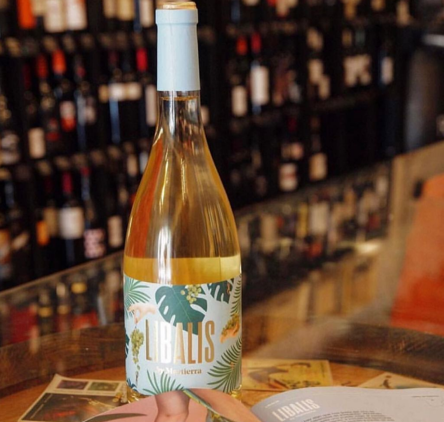 Una botella de vino Pluralis reposa sobre una mesa.