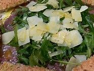 Un primer plano de una ensalada con queso y verduras en un plato.