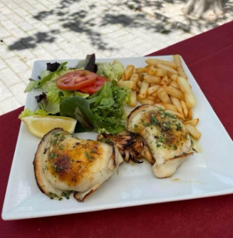 Un plato de comida con patatas fritas y ensalada en una mesa.