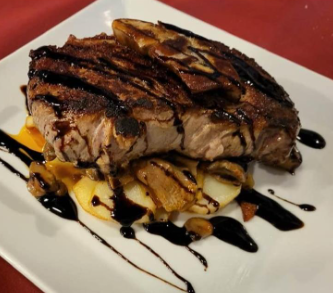 Un plato blanco cubierto con un filete y patatas.