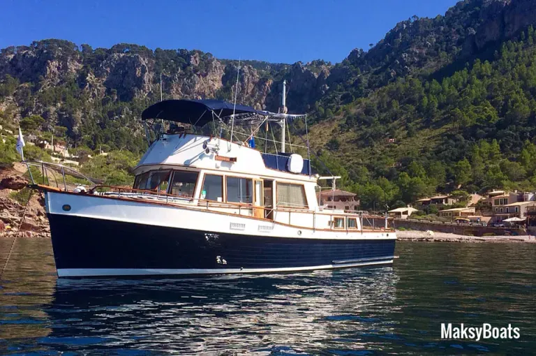 Un barco flota sobre un cuerpo de agua con montañas al fondo.